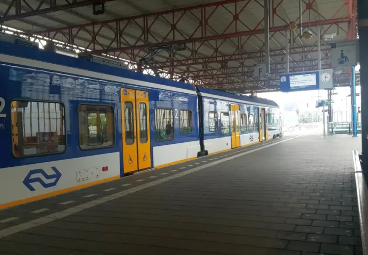 Niebiesko-biały pociąg na stacji, gotowy do podróży z Eindhoven do Amsterdamu.