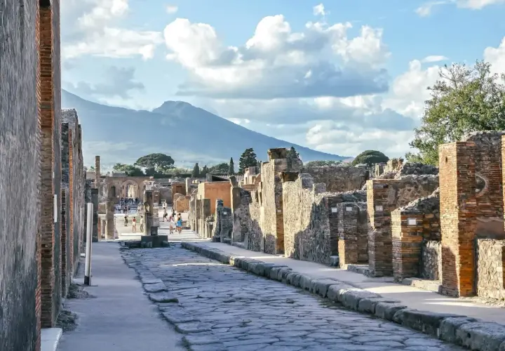 Starożytna droga w Pompejach, z Wezuwiuszem w tle. Idealne miejsce, by poczuć historię i zastanowić się, jak dojechać z Neapolu do Pompejów.