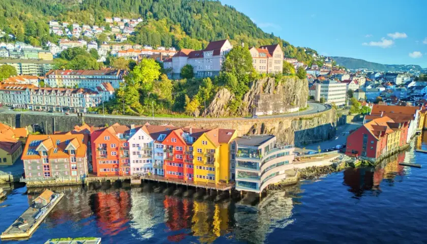 Kolorowe kamienice nad wodą, wzgórza z domkami w tle – to malownicza Norwegia latem.