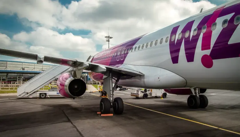 Samolot Wizz Air z fioletowym logo na tle chmur, gotowy do lotu z BVA Paris.