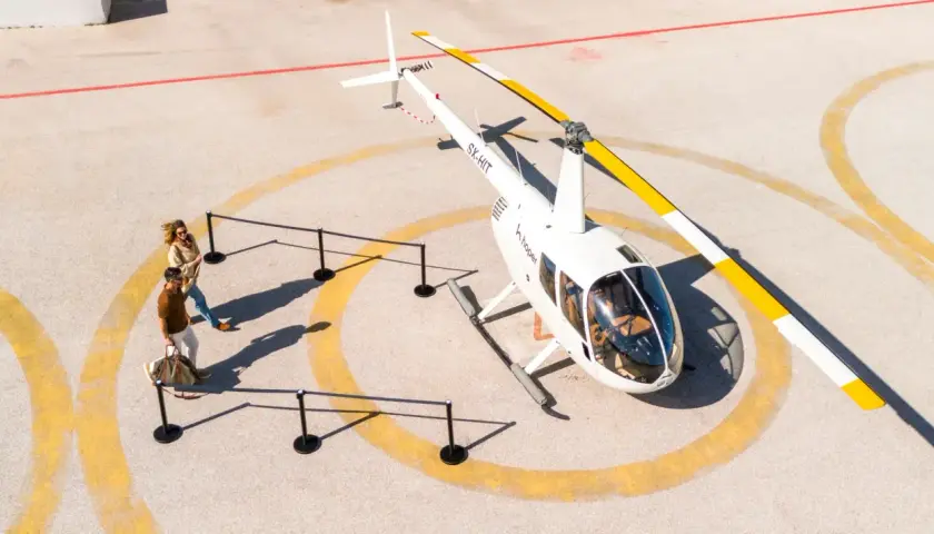 Para zwiedzających zbliża się do helikoptera. Sprawdź hopper ceny biletów na niezapomnianą podróż!