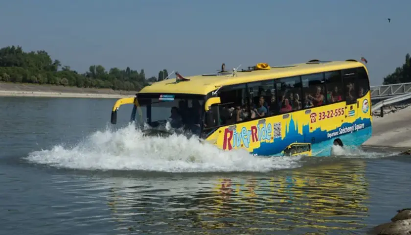 Żółty autobus do Budapesztu, River Ride, wjeżdża do wody, tworząc fale.