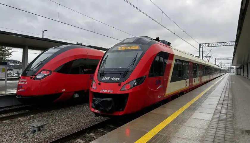 Dwa czerwone pociągi SKM stoją na stacji. Jeden z nich ma na wyświetlaczu informację "SKM Trasa Skrócona", sugerując przebookowanie.