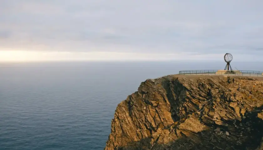 Skała na Nordkapp z globusem i morzem w tle.