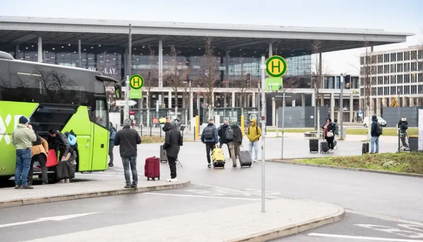 Ludzie z bagażami wsiadają do zielonego autokaru na przystanku autobusowym w Wiedniu Erdberg.