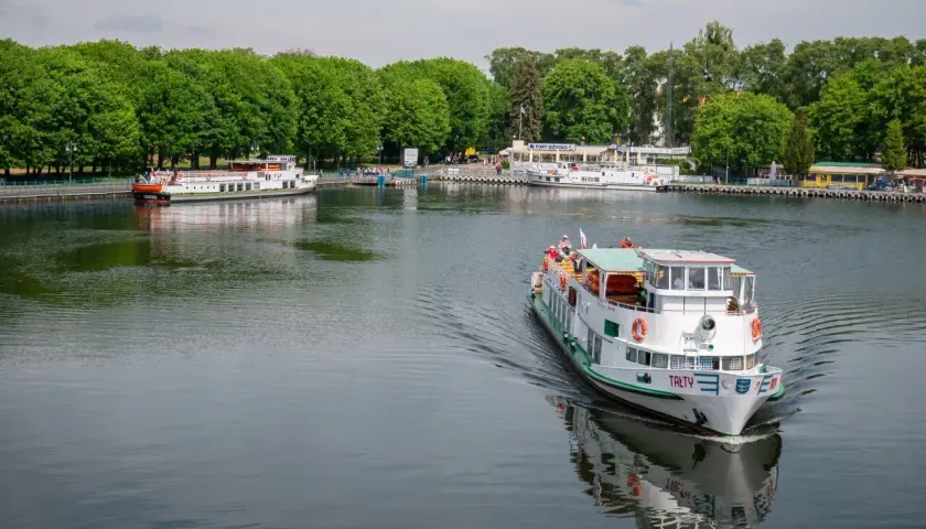 Rejs statkiem po jeziorze w Giżycku, z widokiem na port i zielone drzewa. Podróż z Giżycka do Olsztyna to wspaniała przygoda.