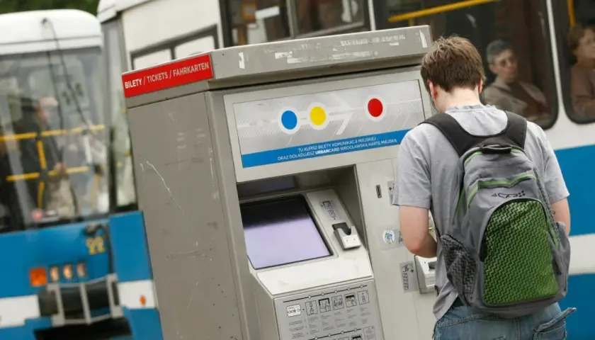Chłopak z plecakiem kupuje bilety MPK Wrocław. Sprawdza ceny biletów na automacie.