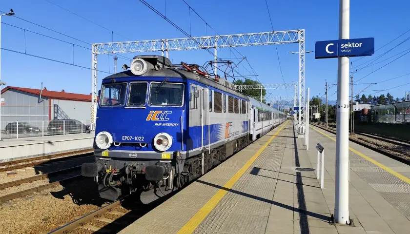 Niebiesko-szara lokomotywa PKP Intercity EP07-1022 na torach. Wyobraź sobie podróż poznań - zakopane pkp bezpośrednio tym pociągiem.