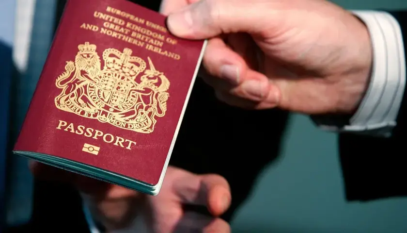 Dłoń trzyma paszport Wielkiej Brytanii. Wkrótce podróż do Norwegii w ramach strefy Schengen.