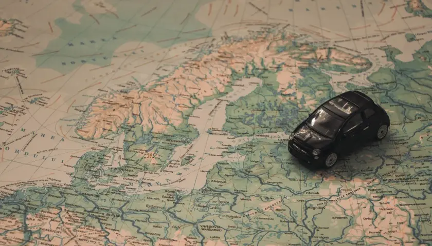 Czarny samochodzik na mapie Europy, planujący trasę jak dojechać do Mikołajek.