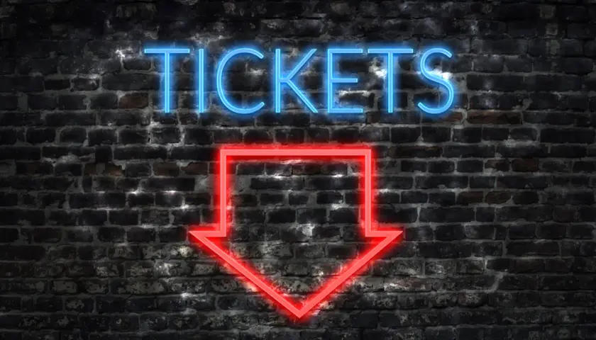 Napis "TICKETS" świeci na niebiesko nad czerwoną strzałką wskazującą w dół. To znak, jak kupić bilet online.