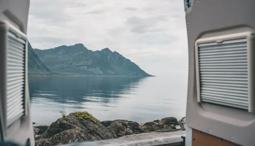 Widok z kampera na spokojne morze i góry w Norwegii. Idealne miejsce na podróż kamperem.