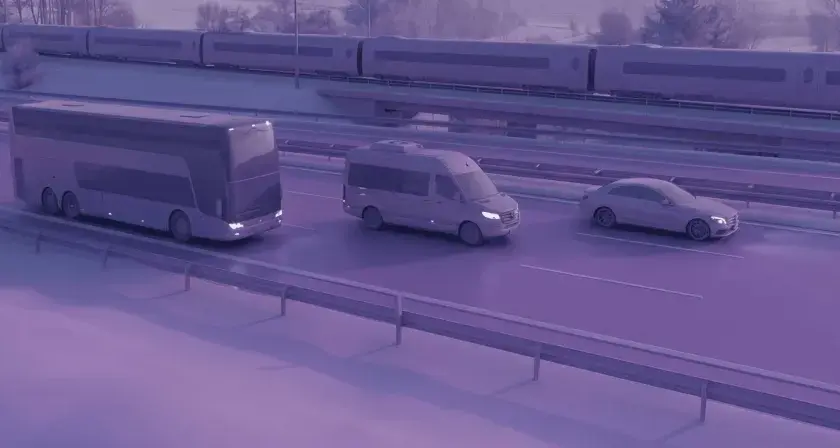 Zastanawiasz się, ile kosztuje bus do Francji? Na drodze widzimy autokar, busa i samochód, a w tle pociąg.