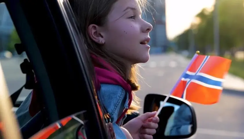 Dziewczynka z flagą Norwegii w ręku, wyjeżdżając samochodem, może symbolizować rejestrację samochodu z Norwegii.