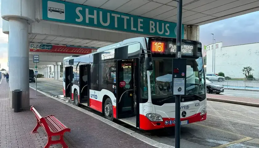 Autobus wahadłowy na lotnisko Bari. Czerwona ławka czeka na pasażerów pod znakiem "SHUTTLE BUS".
