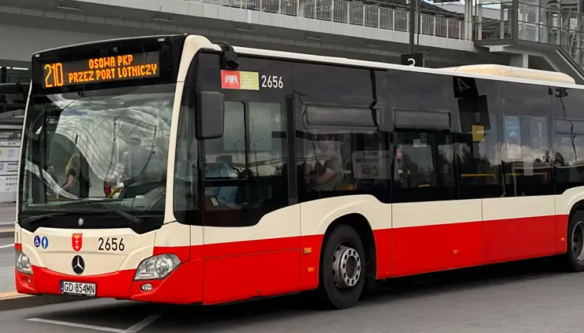 Autobus linii 210 "Przez Port Lotniczy" czeka na pasażerów na przystanku.