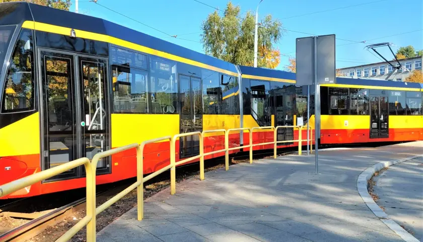 Nowe, nowoczesne grudziądz tramwaje w żółto-czerwonych barwach stoją na torach obok chodnika.