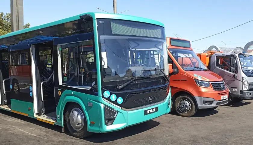 Nowe autobusy i samochody dostawcze stoją obok siebie. Jeden z autobusów, w kolorze turkusowym, ma otwarte drzwi, gotowy do podróży z Augustowa do Łodzi.