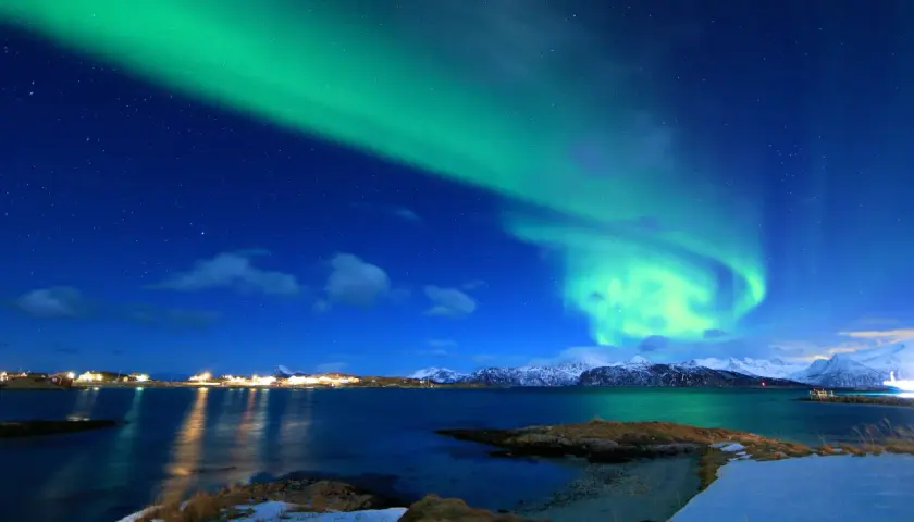 Zielona zorza polarna nad norweską wioską. Ciekawe ciekawostki o Norwegii: to zjawisko można podziwiać zimą.
