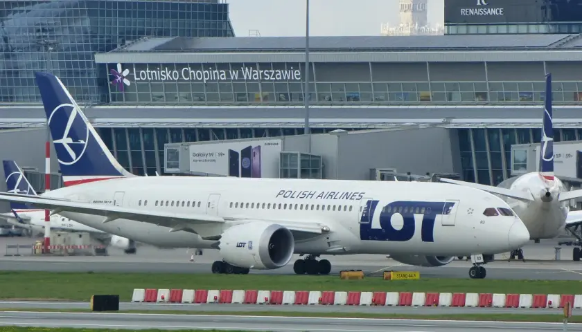 Samolot LOT Polish Airlines na płycie lotniska Chopina w Warszawie. W tle budynek terminala.