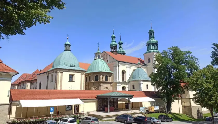 Kraków Kalwaria Zebrzydowska: imponujący zespół klasztorny z zielonymi kopułami i wieżami, otoczony parkingiem i drzewami.