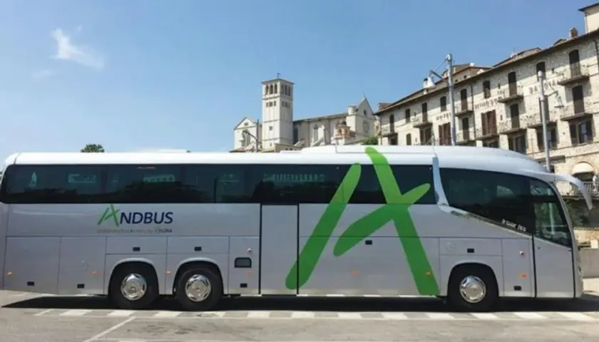 Autokar ANDBUS, idealny na podróż z Barcelony do Andory, parkuje przed zabytkową zabudową.