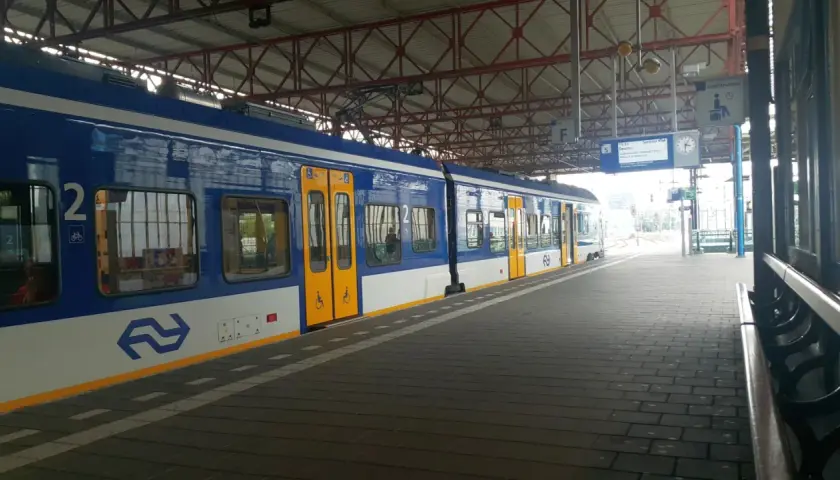 Niebiesko-biały pociąg na stacji, gotowy do podróży z Eindhoven do Amsterdamu.