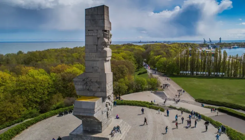 Westerplatte zwiedzanie: monumentalny Pomnik Obrońców Wybrzeża i spacerujący turyści na tle zieleni i morza.