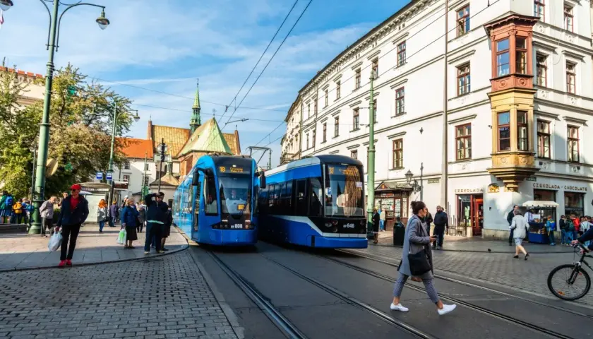 Kraków: dwa niebieskie tramwaje na ulicy, ludzie czekają na przystanku. Idealne na bilet godzinny Kraków.