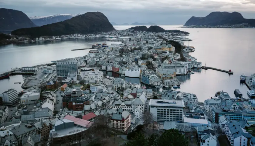 Widok na malownicze miasta w Norwegii, z charakterystyczną architekturą i portem, otoczone wodą i górami.