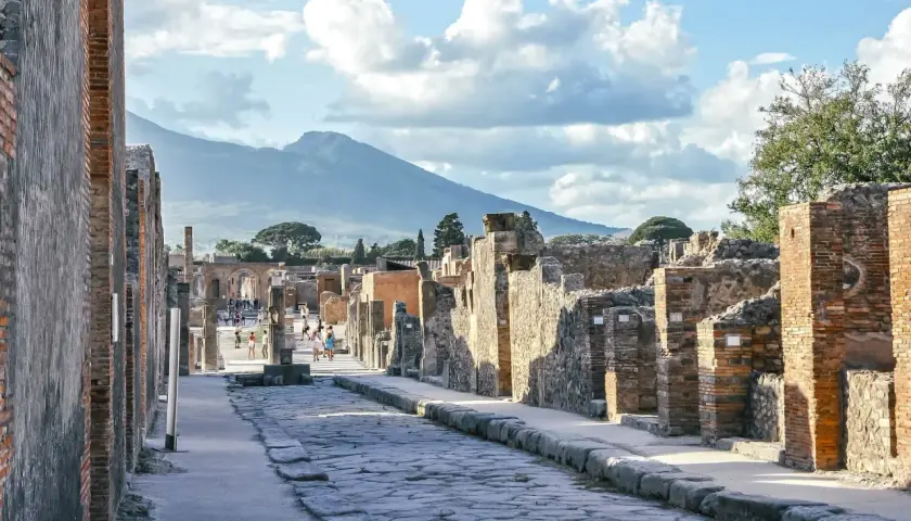 Starożytna droga w Pompejach, z Wezuwiuszem w tle. Idealne miejsce, by poczuć historię i zastanowić się, jak dojechać z Neapolu do Pompejów.