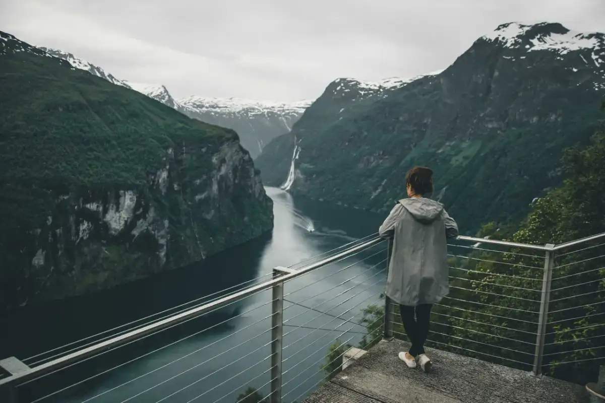 Widok na fiordy w Norwegii. Kobieta podziwia majestatyczne góry i wodę.