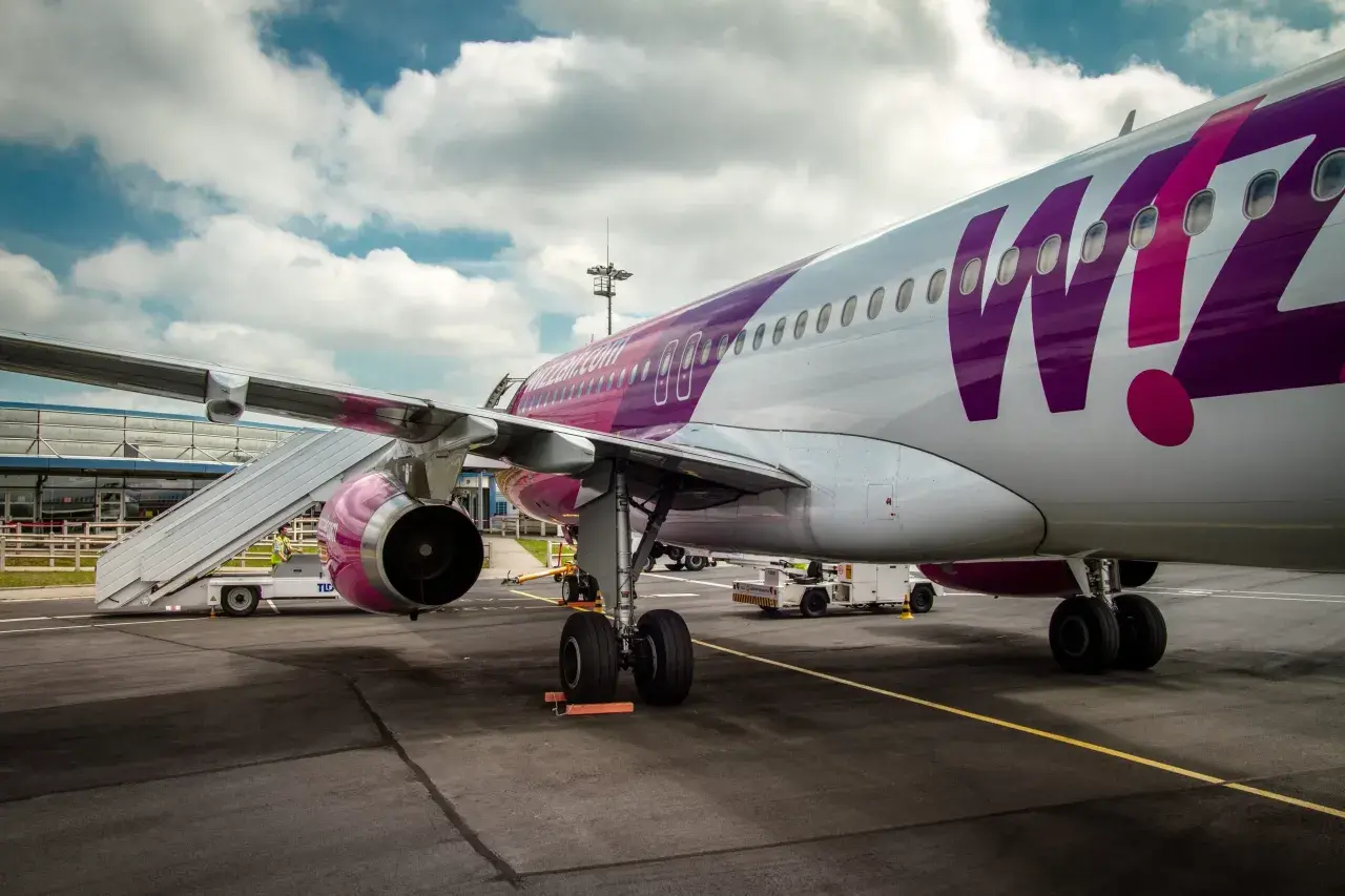 Samolot Wizz Air z fioletowym logo na tle chmur, gotowy do lotu z BVA Paris.