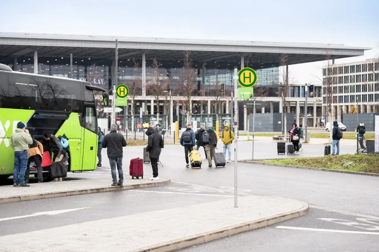 Ludzie z bagażami wsiadają do zielonego autokaru na przystanku autobusowym w Wiedniu Erdberg.