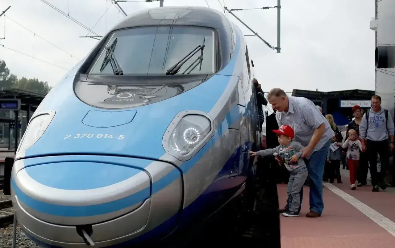 Rodzina podziwia nowoczesny pociąg Pendolino. Sprawdzają pociąg warszawa - gdańsk cena, by zaplanować podróż.