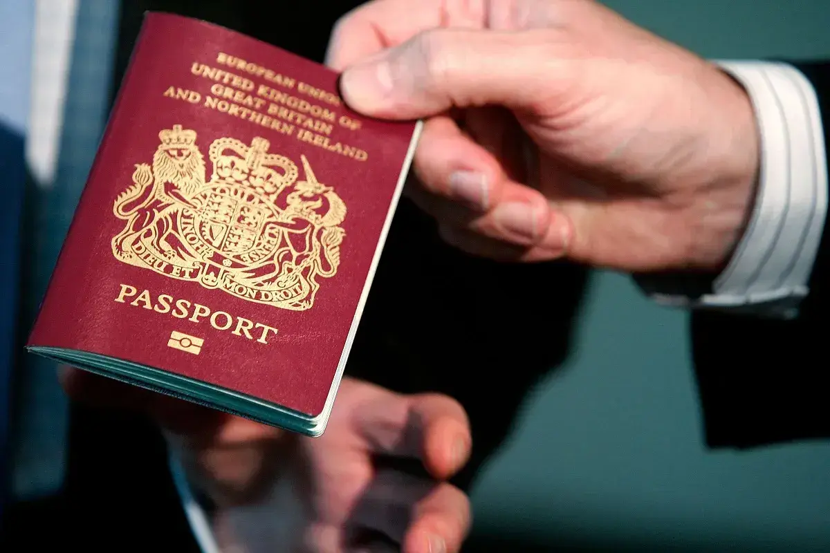 Dłoń trzyma paszport Wielkiej Brytanii. Wkrótce podróż do Norwegii w ramach strefy Schengen.