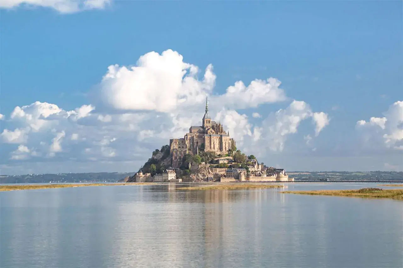 Majestatyczny Le Mont Saint-Michel, średniowieczny klasztor na skalistej wyspie, wznosi się nad spokojną wodą.