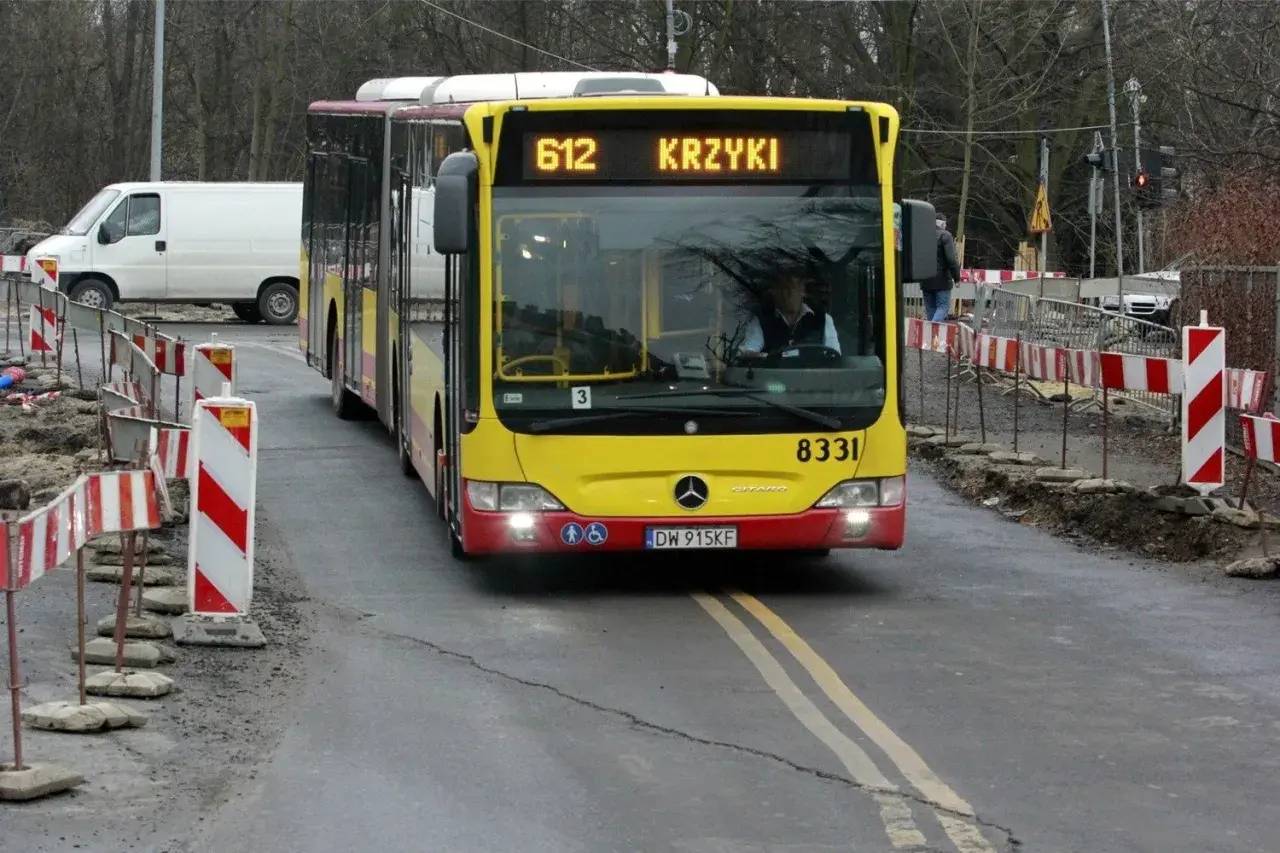 Autobus MPK linii 612 z napisem "KRZYKI" jedzie po drodze z robotami drogowymi. Jak dojechać na Bielany Wrocławskie MPK? Ten autobus może być odpowiedzią.