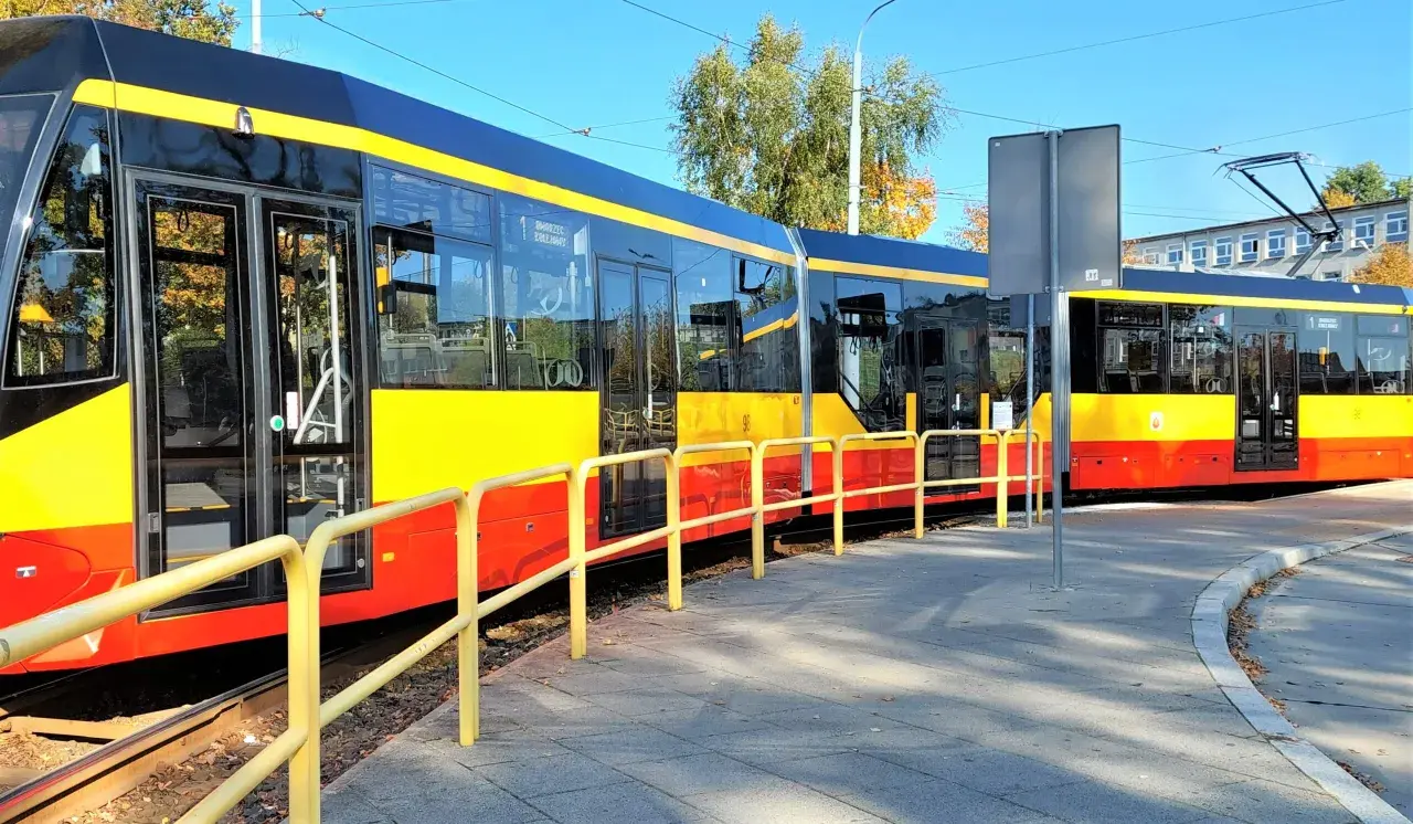 Nowe, nowoczesne grudziądz tramwaje w żółto-czerwonych barwach stoją na torach obok chodnika.