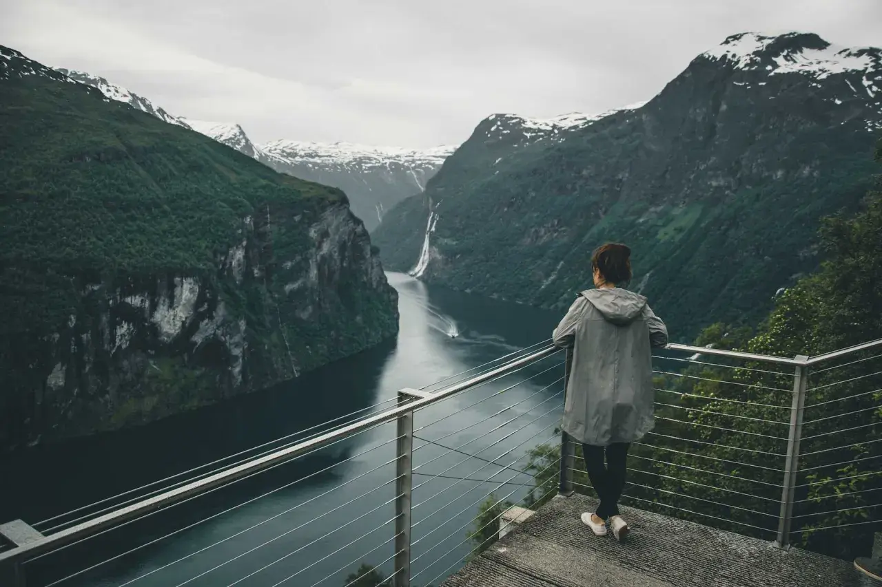 Widok na fiordy w Norwegii. Kobieta podziwia majestatyczne góry i wodę.