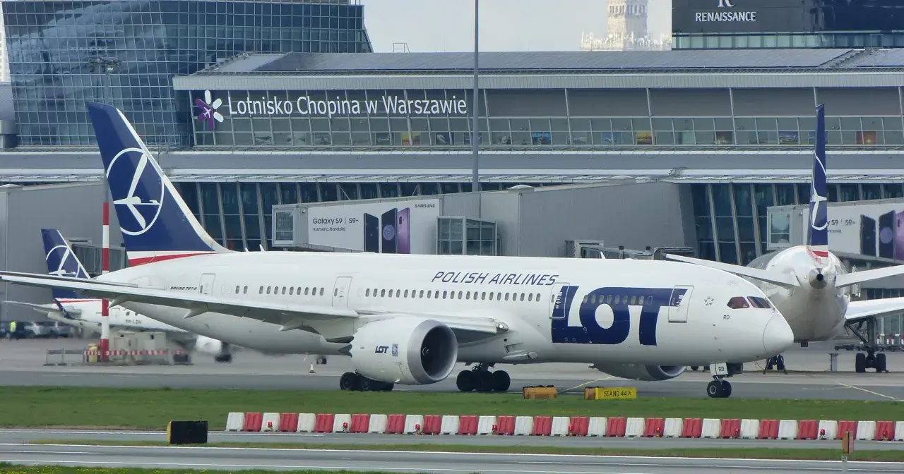 Samolot LOT Polish Airlines na płycie lotniska Chopina w Warszawie. W tle budynek terminala.
