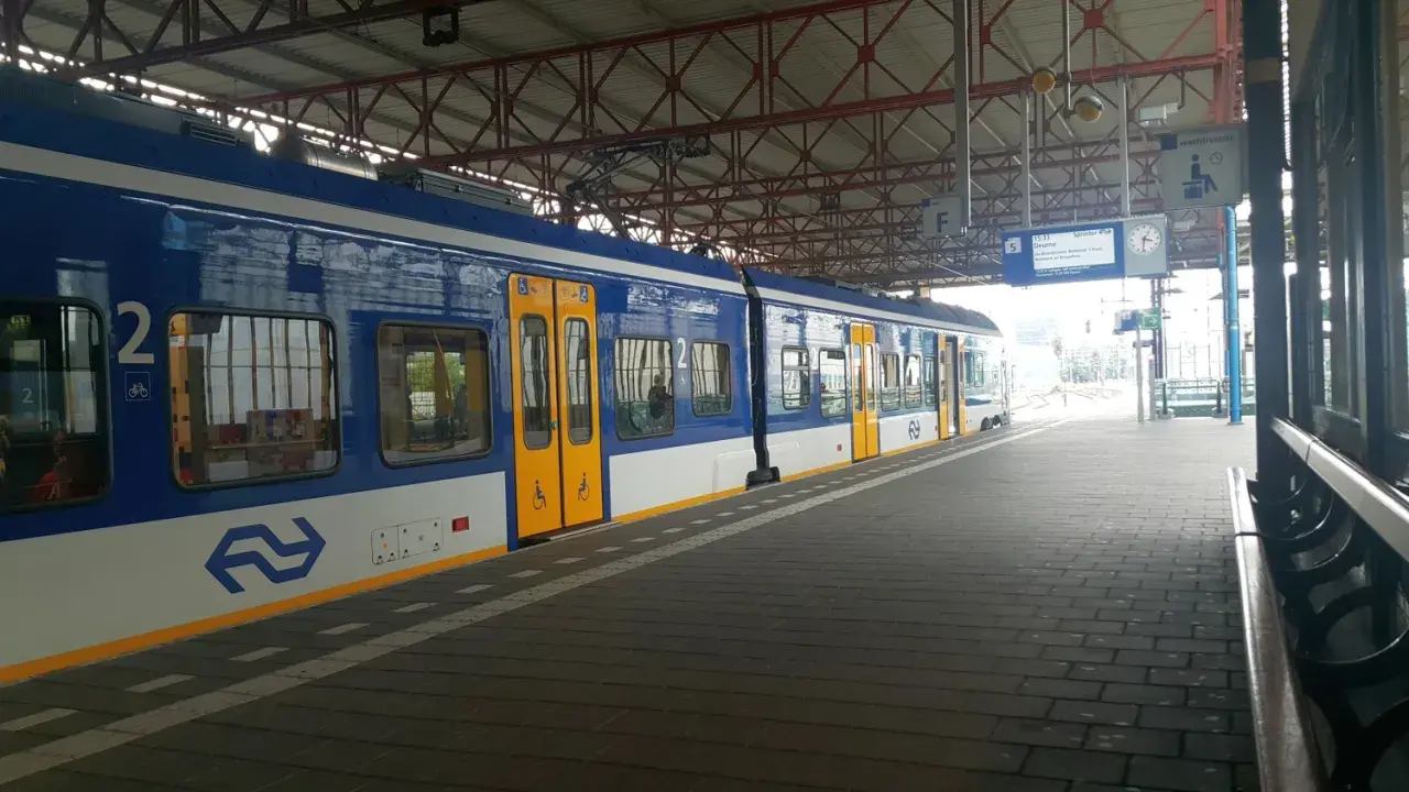 Niebiesko-biały pociąg na stacji, gotowy do podróży z Eindhoven do Amsterdamu.
