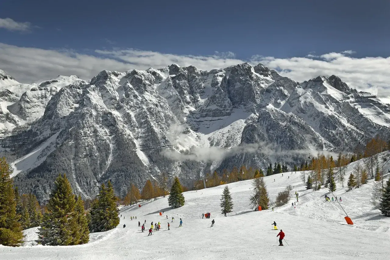Narciarze szusują po ośnieżonych stokach w Marilleva, pod majestatycznymi, skalistymi szczytami Dolomitów.