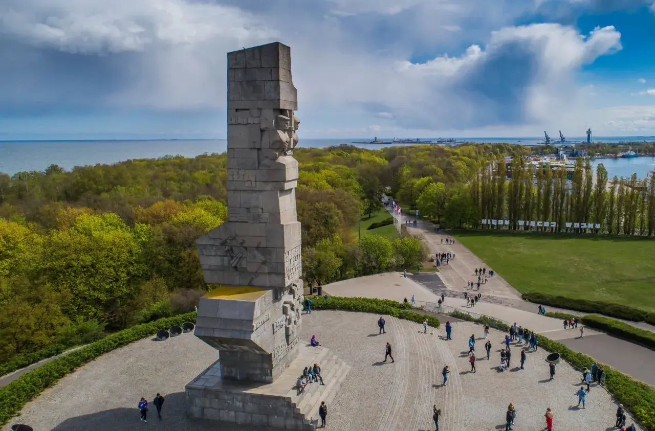 Westerplatte zwiedzanie: monumentalny Pomnik Obrońców Wybrzeża i spacerujący turyści na tle zieleni i morza.