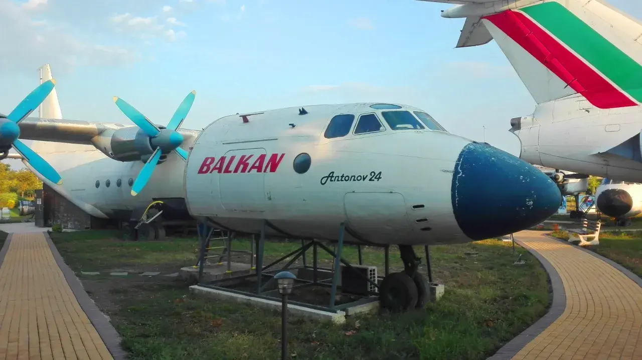 Antonov 24 z napisem BALKAN, jeden z samolotów na bułgarskich lotniskach, stoi na trawie obok ścieżki.