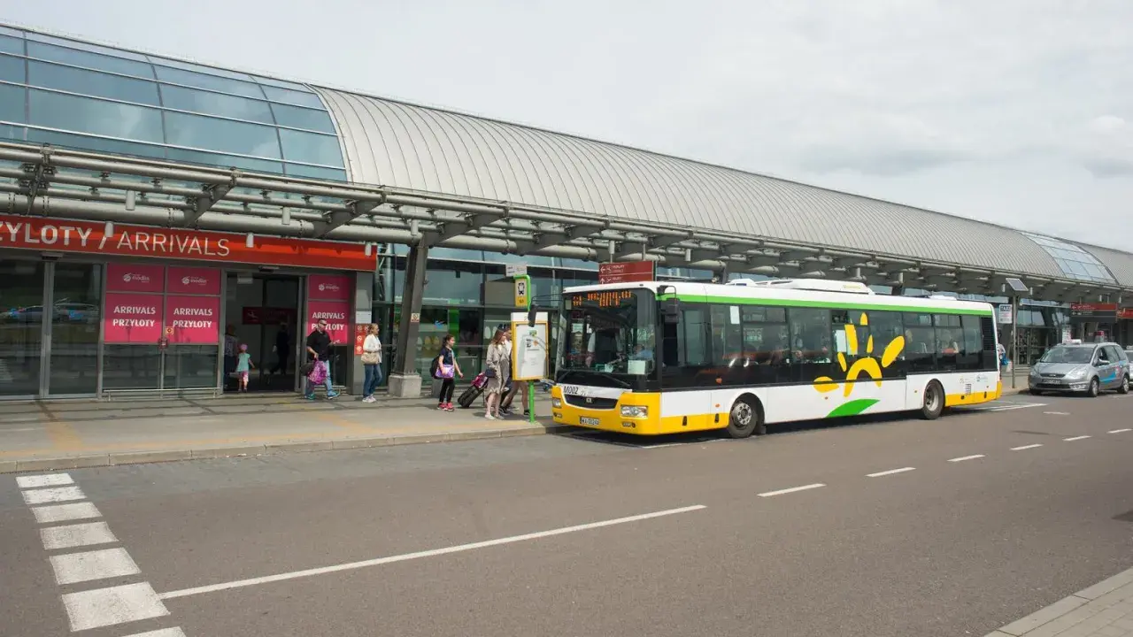 Autobus z logo Modlin Airport czeka na pasażerów przy terminalu.