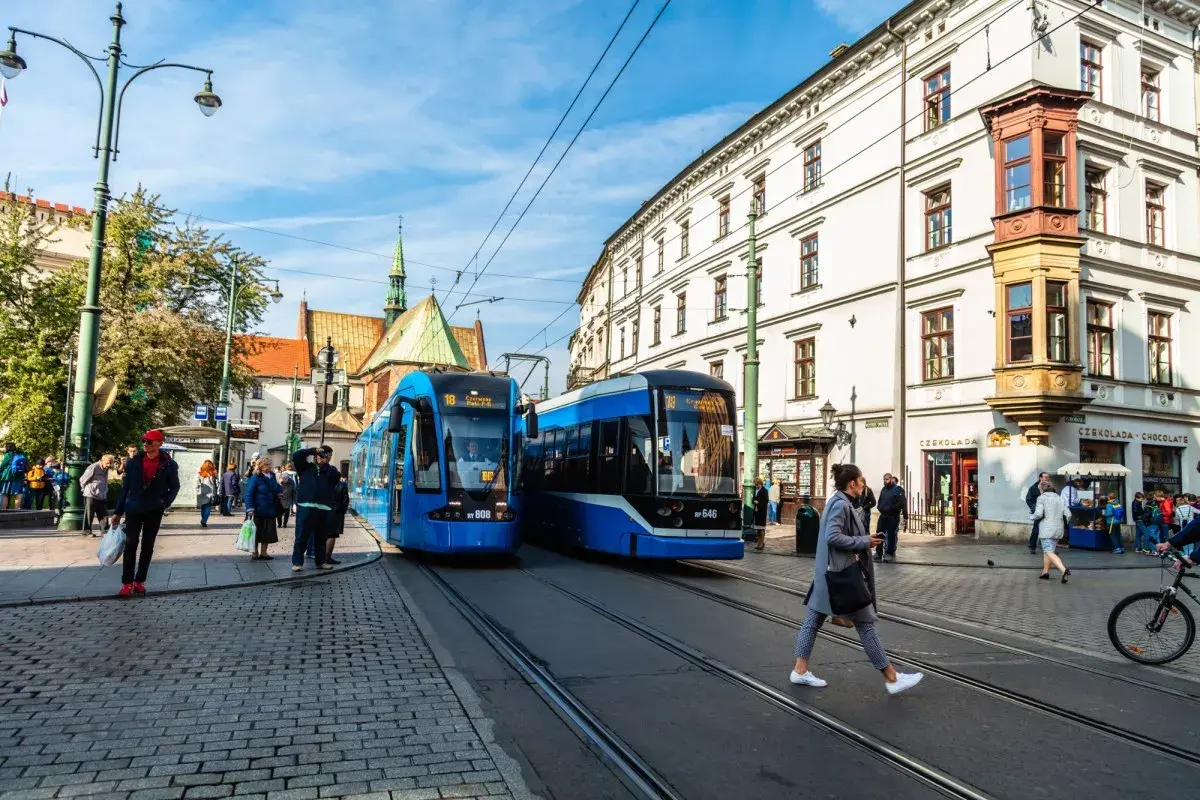 Kraków: dwa niebieskie tramwaje na ulicy, ludzie czekają na przystanku. Idealne na bilet godzinny Kraków.