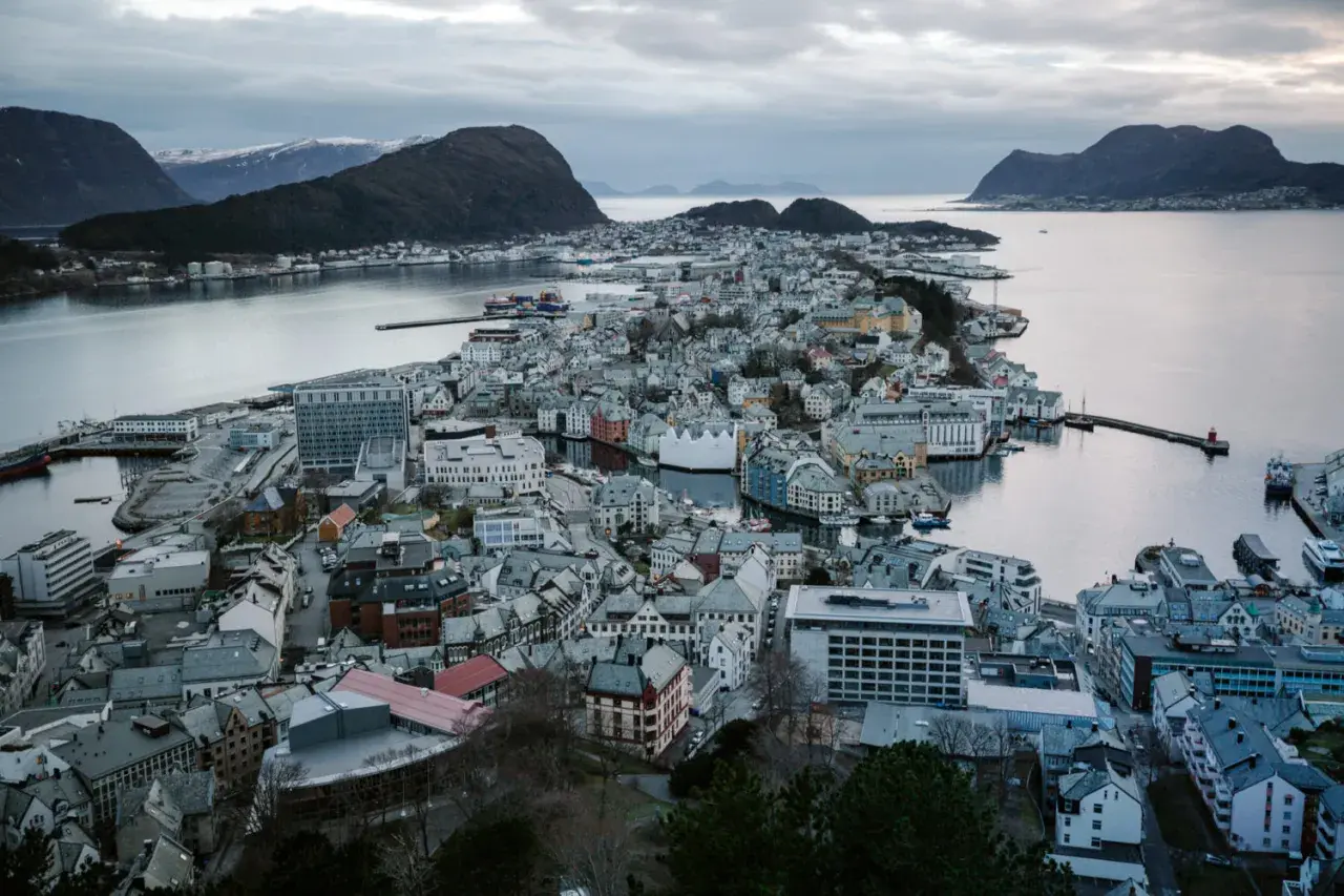 Widok na malownicze miasta w Norwegii, z charakterystyczną architekturą i portem, otoczone wodą i górami.