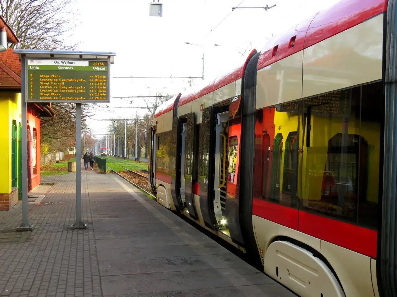 Tramwaj na przystanku w Gdańsku, obok tablica z rozkładem jazdy. Gdański transport publiczny w akcji.