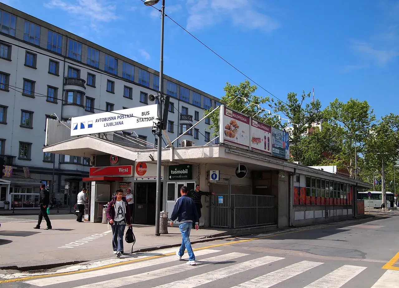 Autobus ze Słowenii na dworcu w Lublanie. Ludzie przechodzą przez pasy.